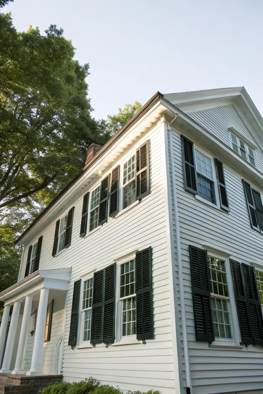 A colonial-style house showcasing traditional white vinyl siding and bold dark window coverings.