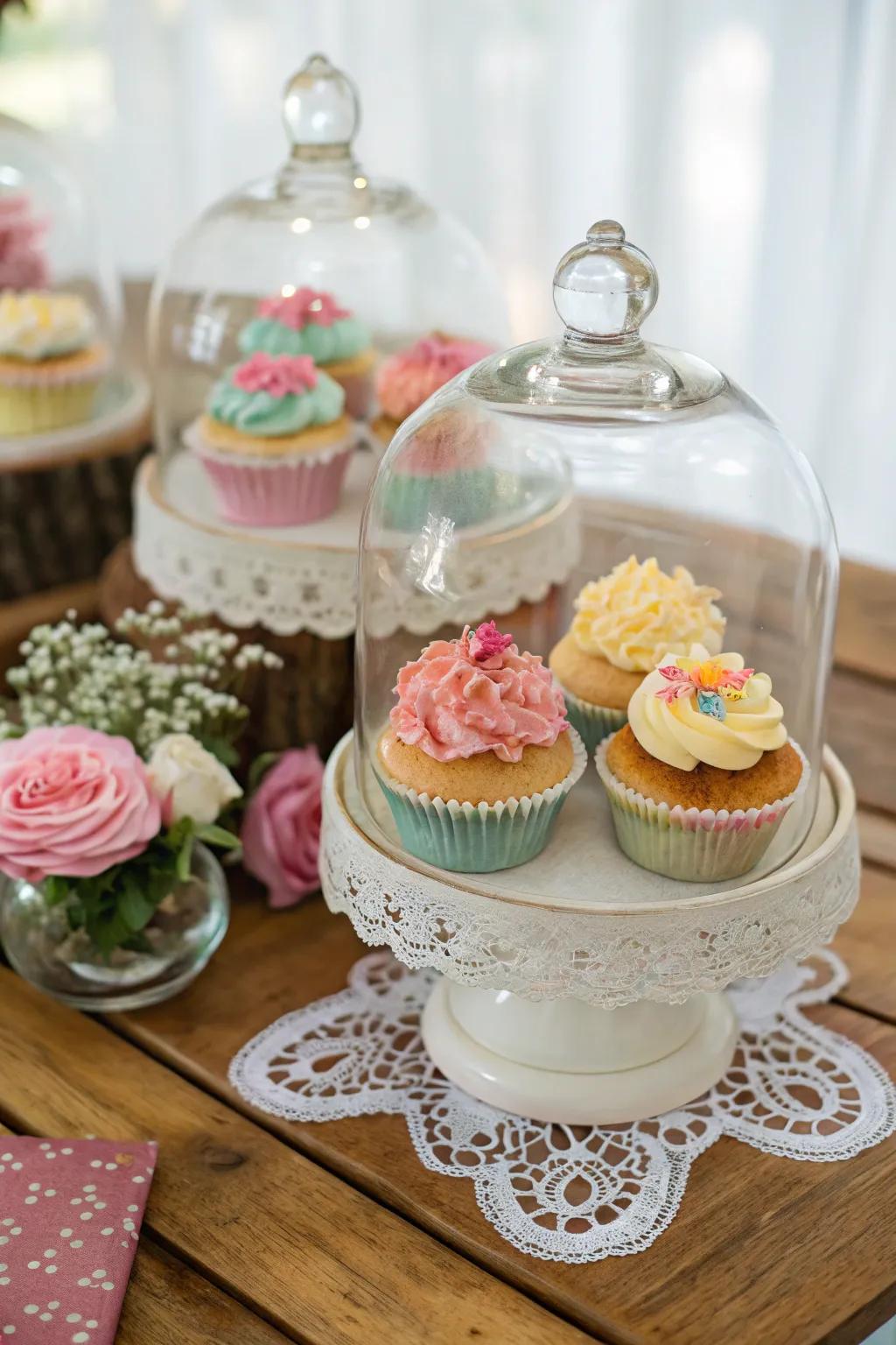 An elegant cupcake display, protected by glass cloches.