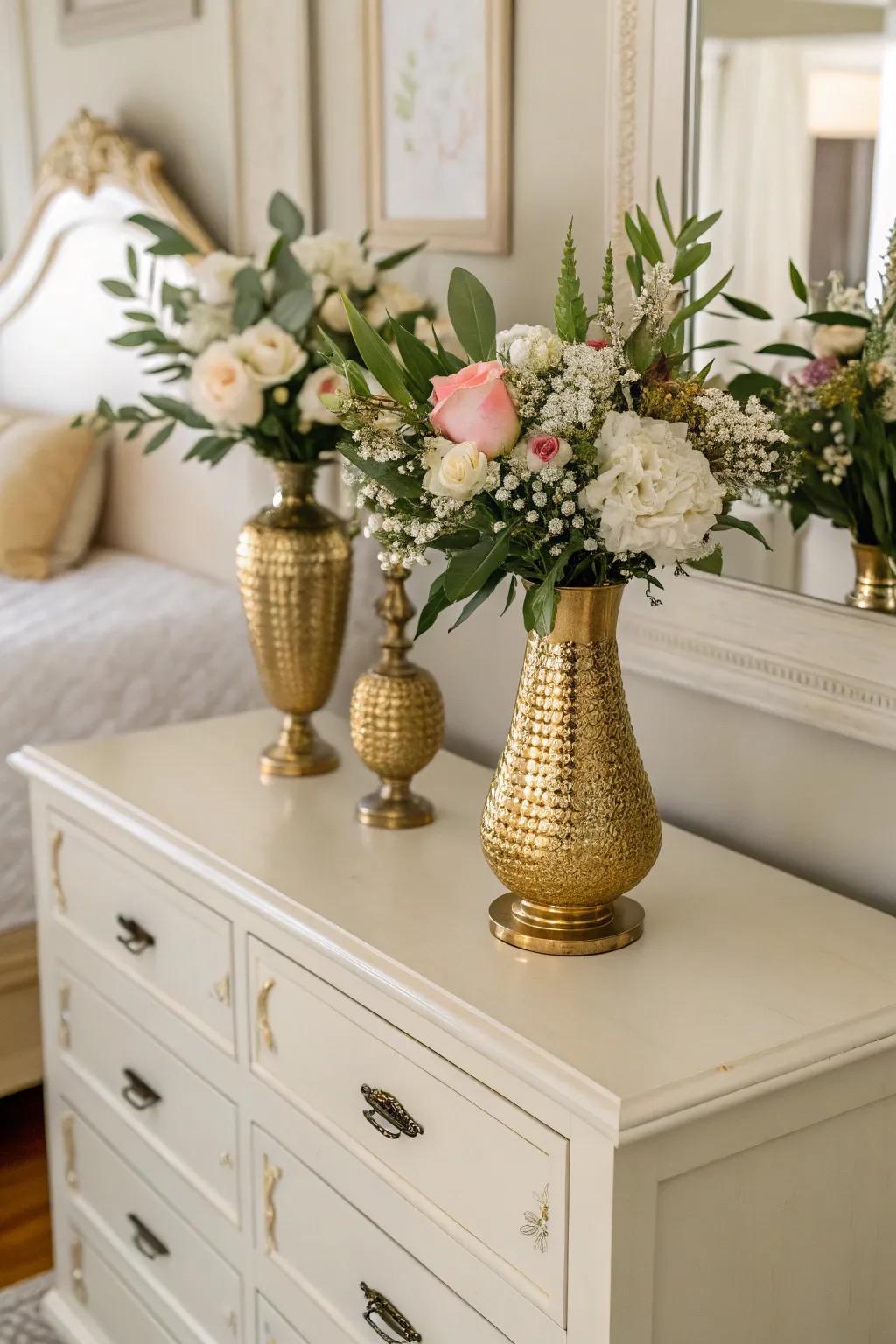 Gold vases alongside blossoms inject both nature and elegance into the bedroom.
