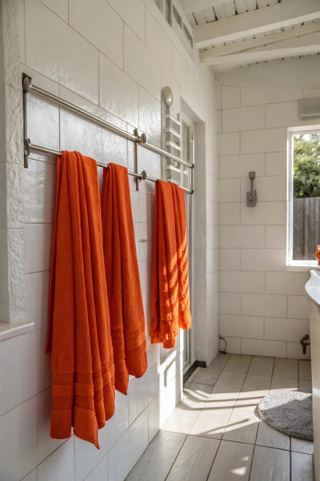 A pristine white bathroom brightened with vibrant orange towels, adding a burst of color.