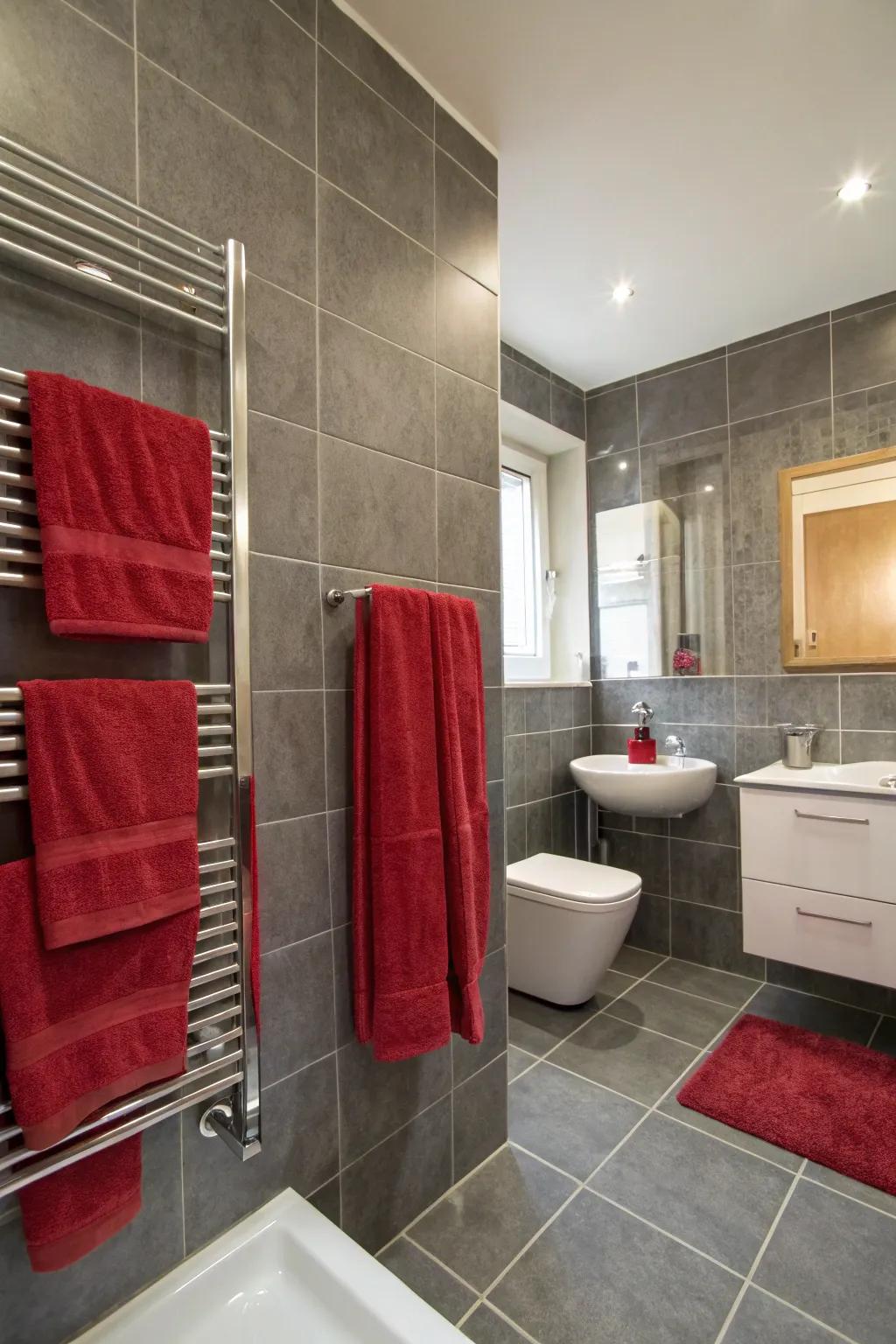 A bathroom featuring grey tiles and a splash of crimson.