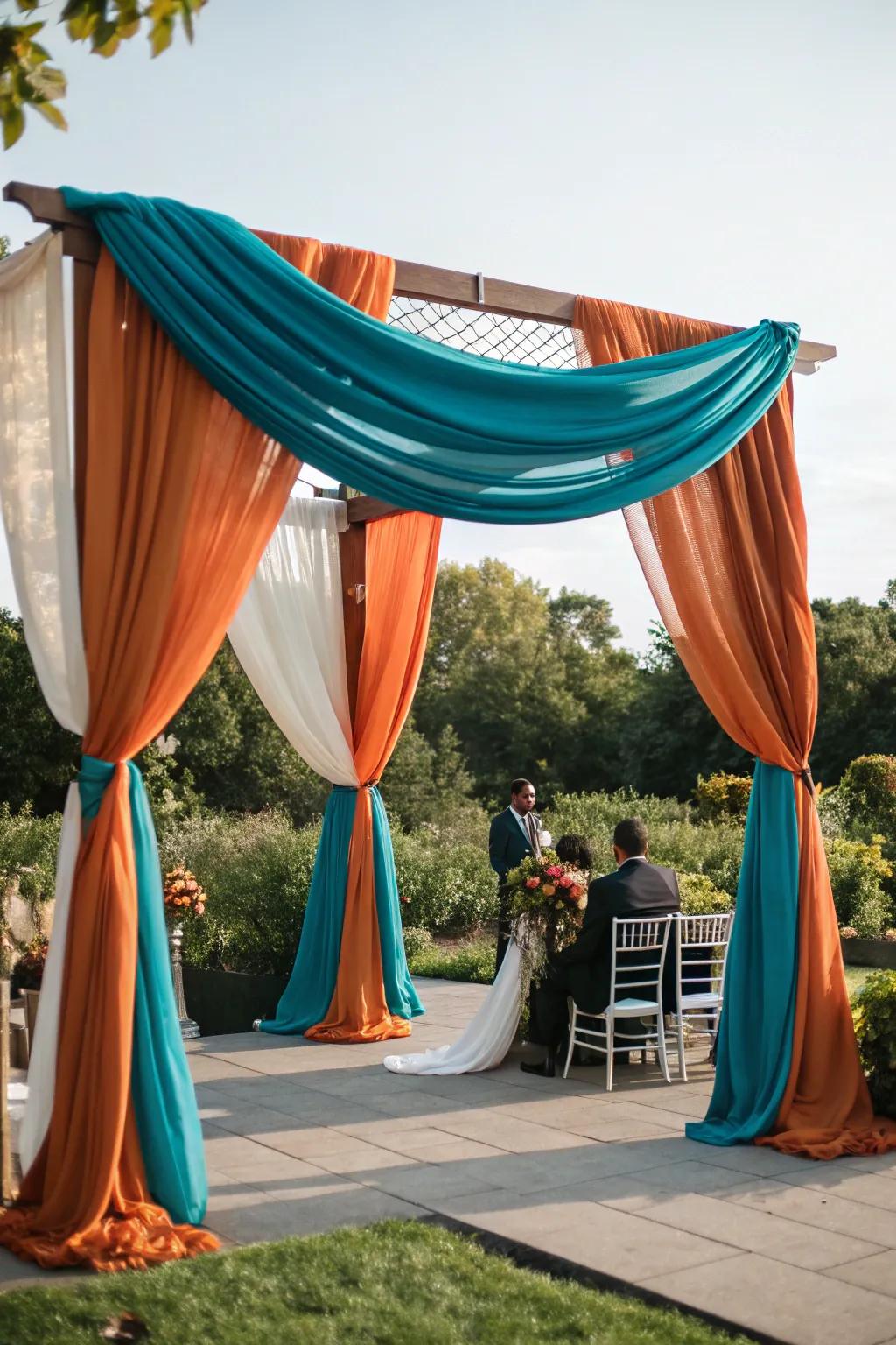 A ceremony arch draped in stunning ocean and sunset-hued textiles.